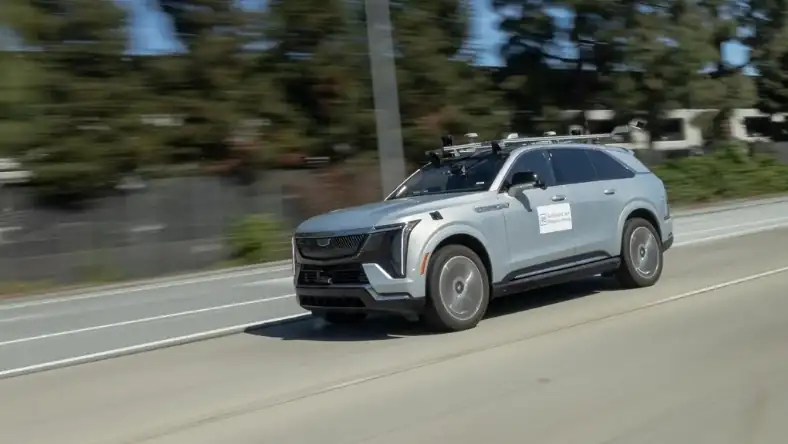 A self-driving test vehicle with roof-mounted sensors and research labelling travelling on a multi-lane road