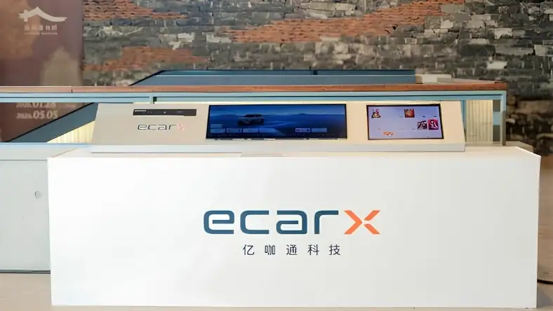 White exhibition stand with a control panel and two angled screens above, backed by an exposed brick wall